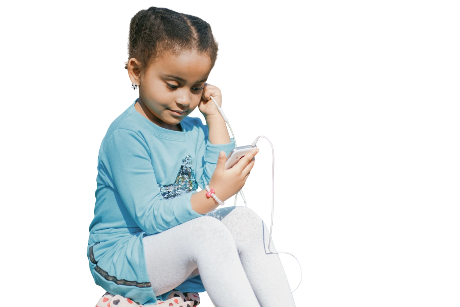 Uma criança com fones de ouvido, olhando para o aparelho que segura.